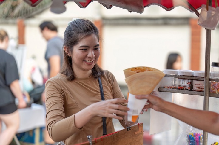 A student on a French language educational trip being handed a crepe.